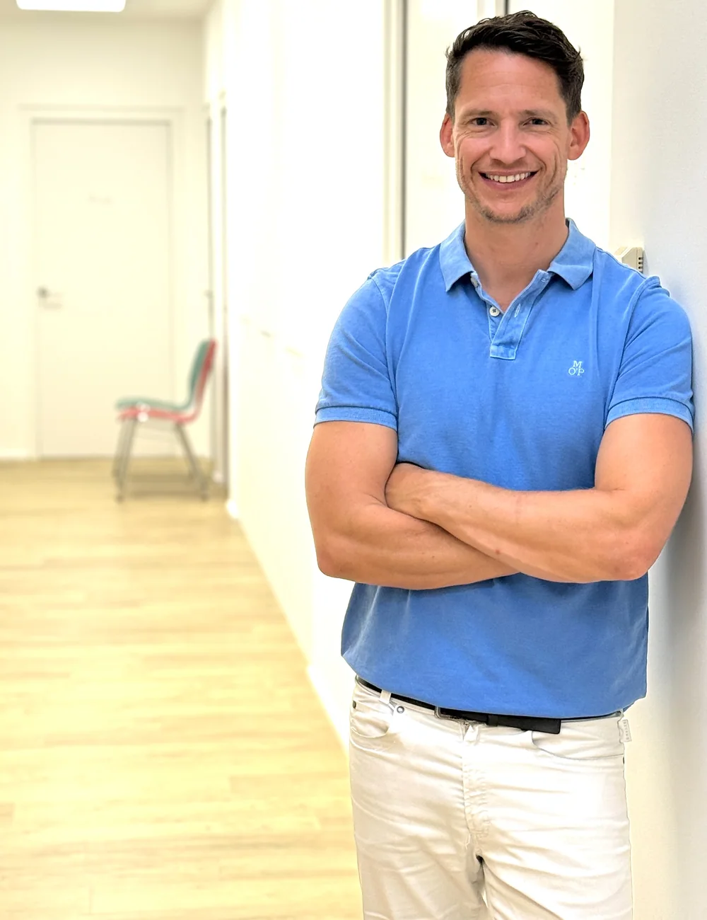 Dr. Tobias Gmeiner im blauen Poloshirt im Gang der Praxis